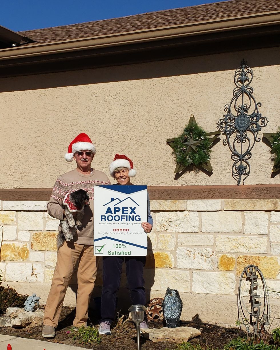 Couple in Christmas Attire holding APEX Roofing sign