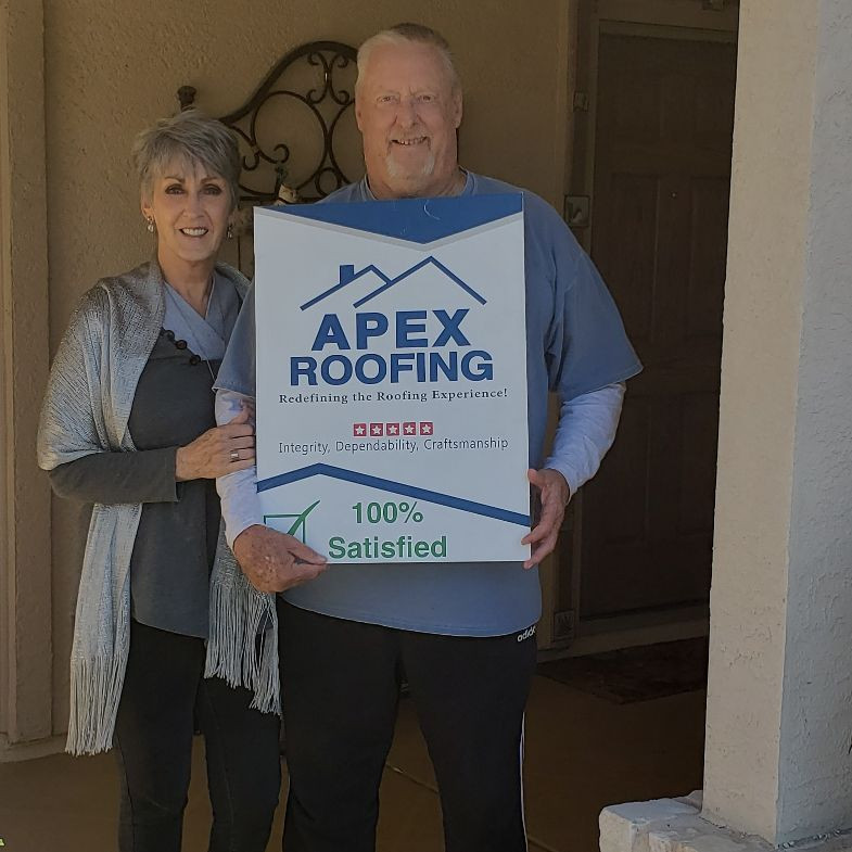 Couple Holding APEX Roofing Sign after Services were Completed