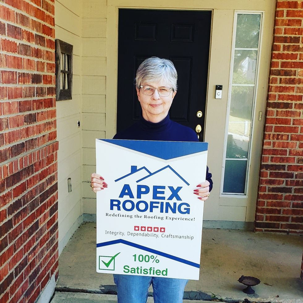 Woman Holding APEX Roofing Sign after Residential Services were Completed